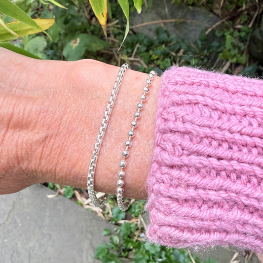 silver bracelets close up on arm with pink sweater
