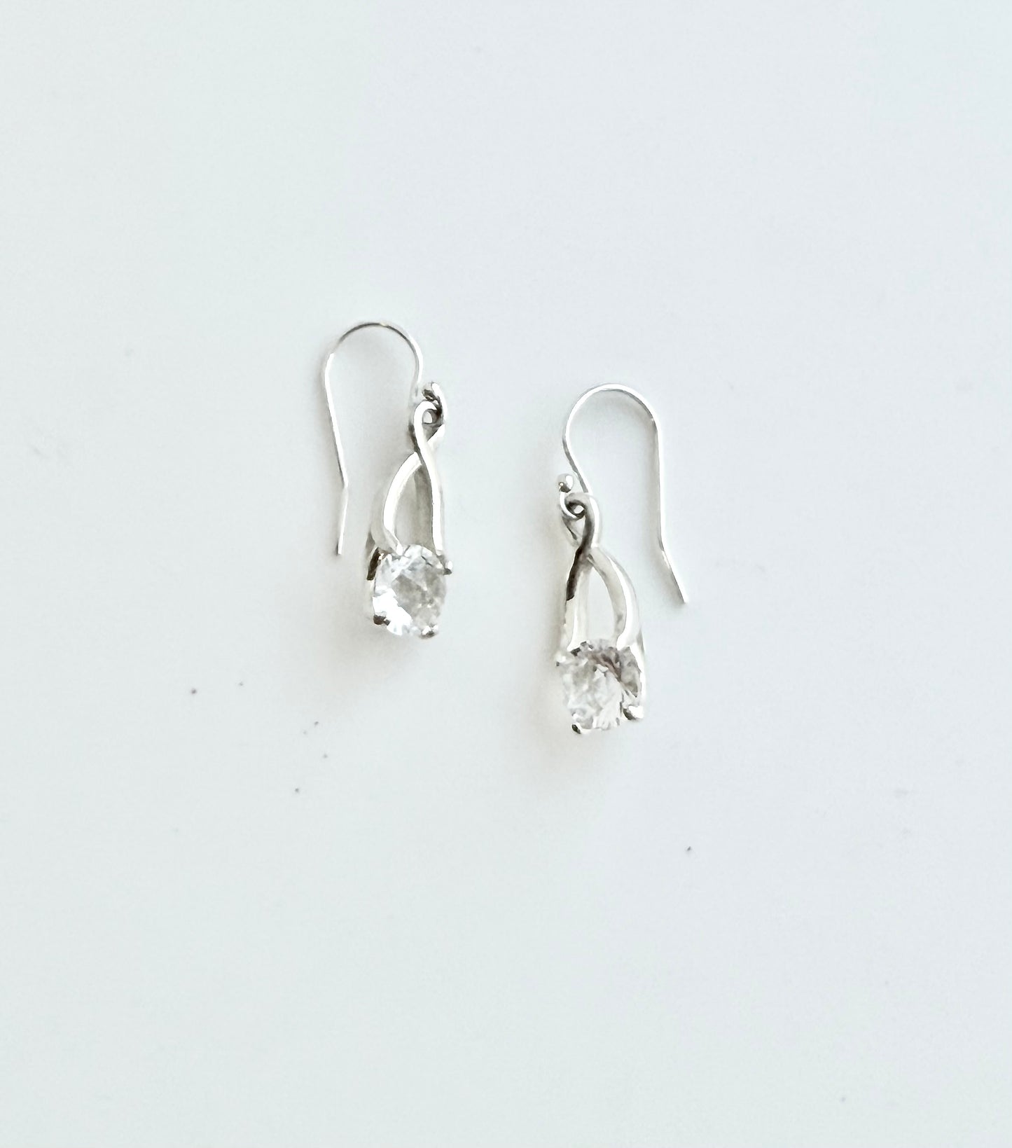 Pair of silver earrings with clear stones on a white background