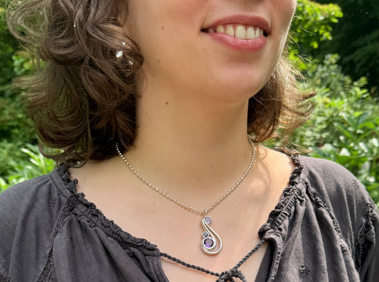 Woman wearing a necklace with a pendant outdoors