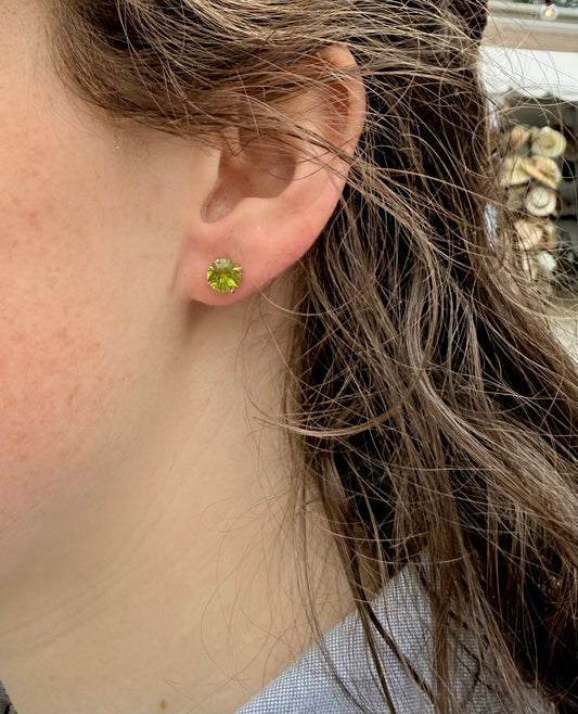Close-up of a person wearing a green stud earring