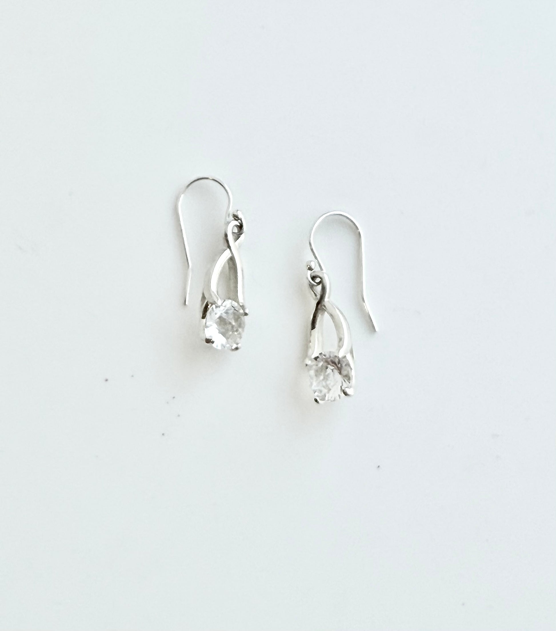 Pair of silver earrings with clear stones on a white background