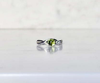 silver ring with green gemstone resting on marble 