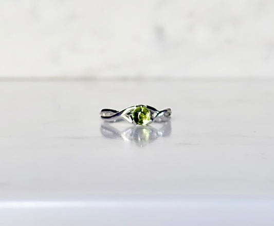 silver ring with green gemstone resting on marble 