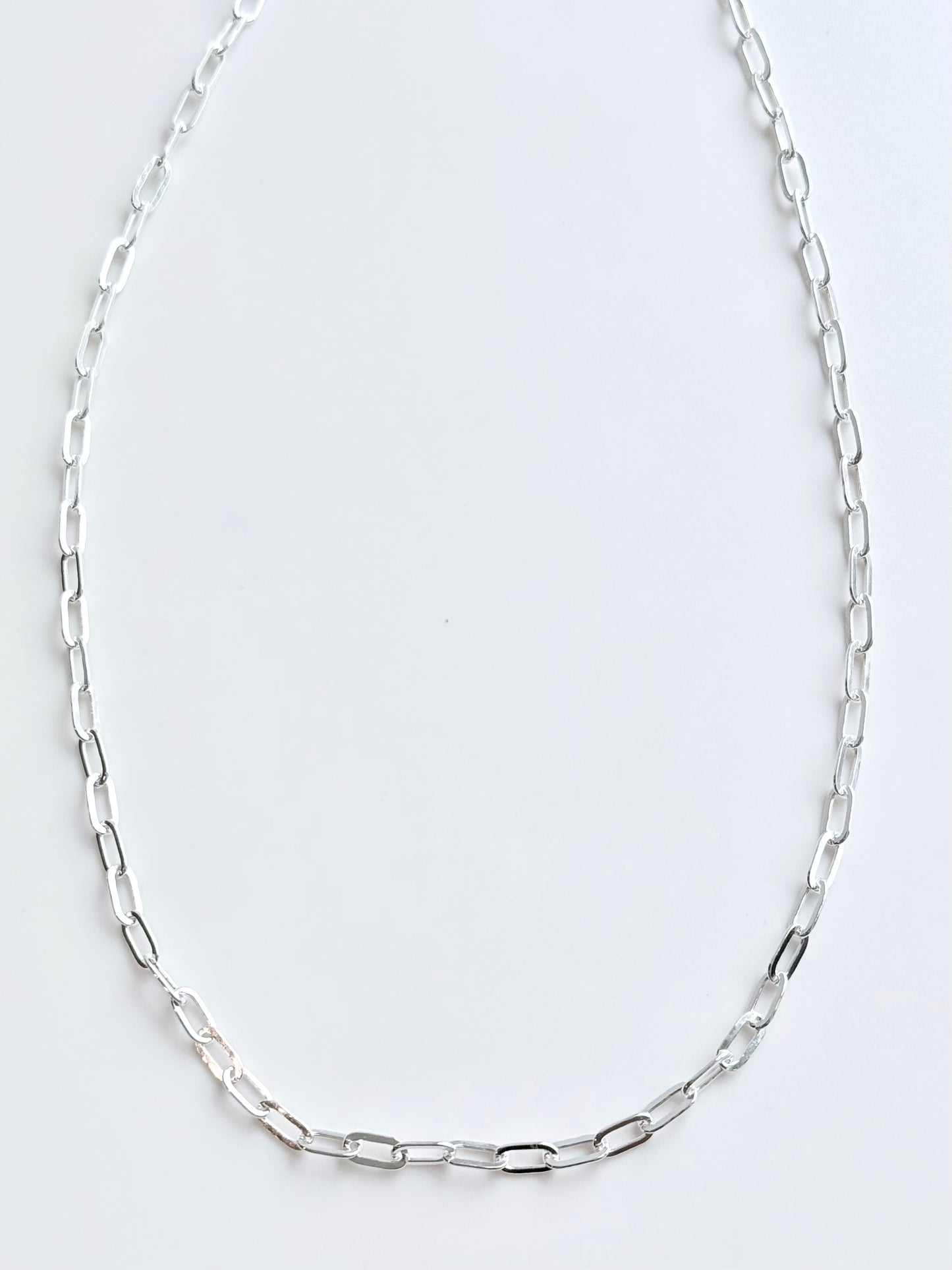 Silver chain necklace on a light gray background