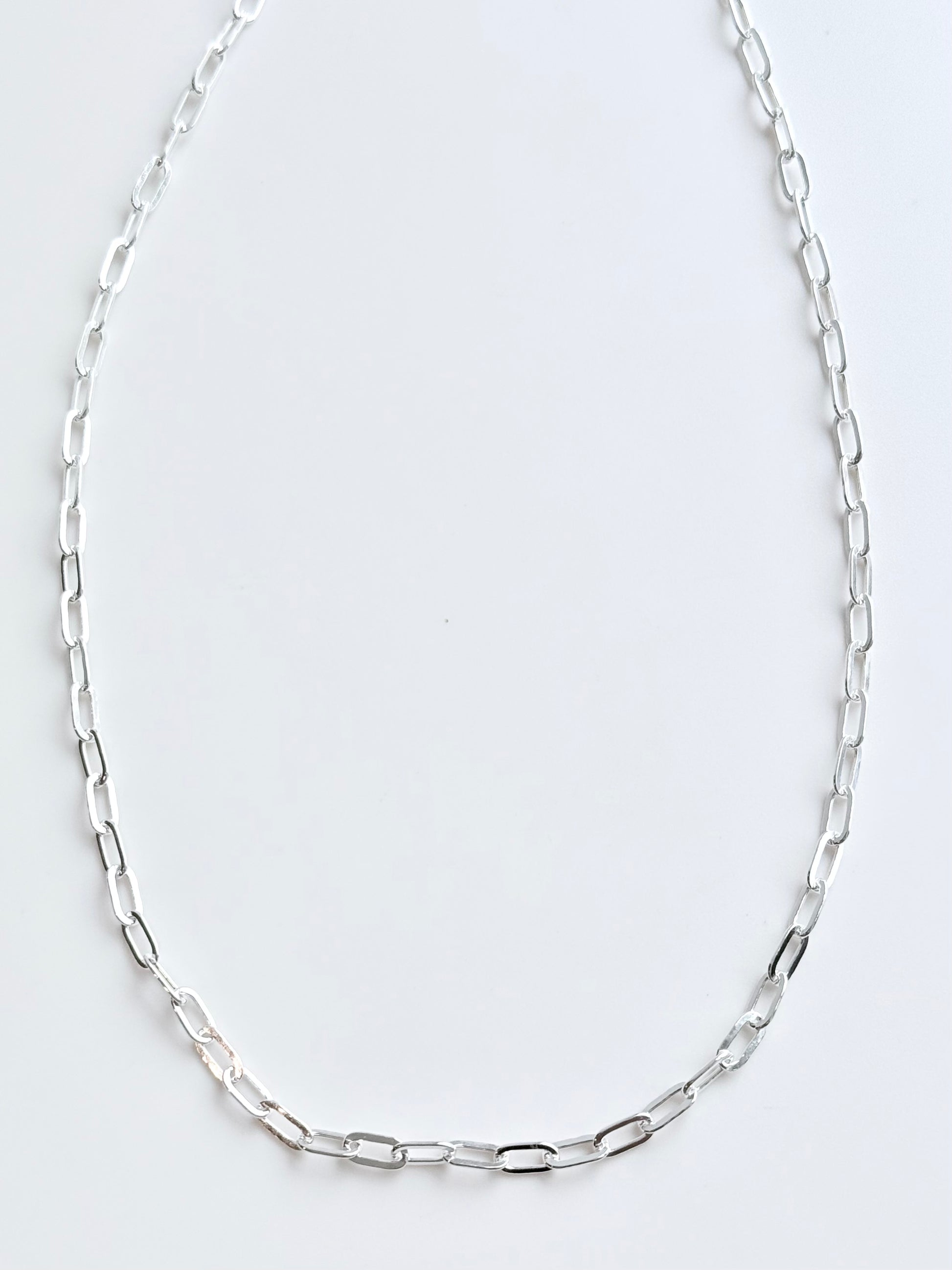 Silver chain necklace on a light gray background