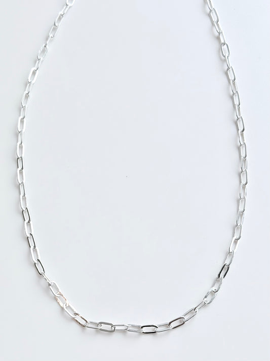 Silver chain necklace on a light gray background