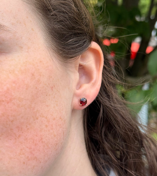 Close-up of an ear with a red garnet stud earring 