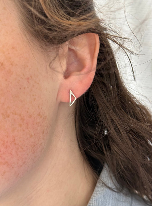 Close-up of an ear wearing a triangle-shaped earring.