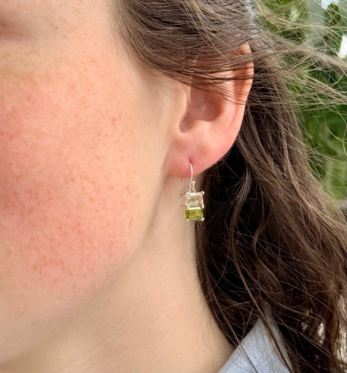 Close-up of a person wearing a green gemstone earring.