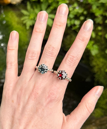 Hand wearing two decorative rings with a natural background