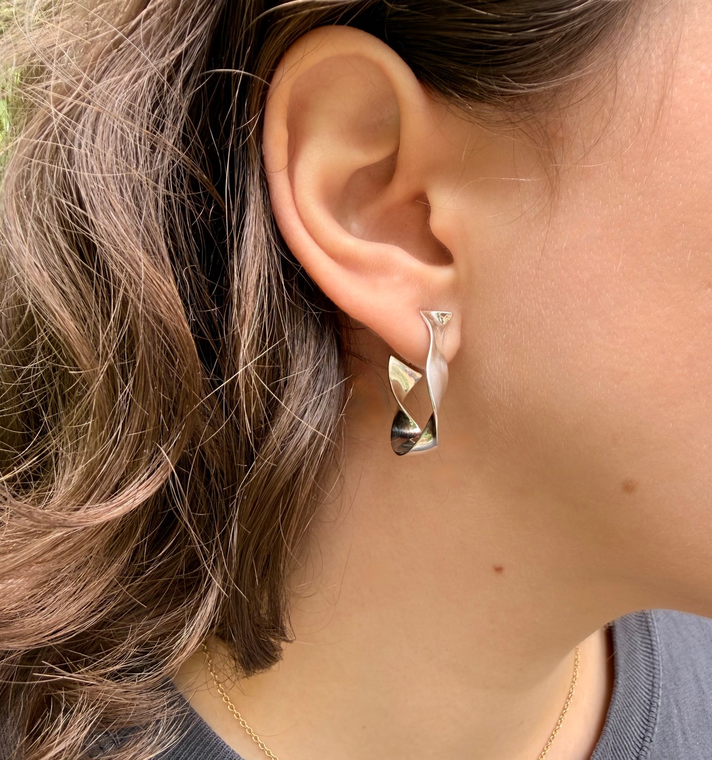 Close-up of an ear wearing a silver earring with face turned sideways