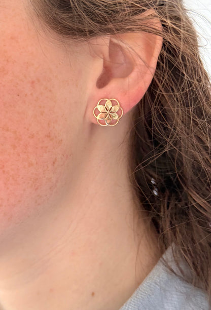 Gold floral earring worn by a person 