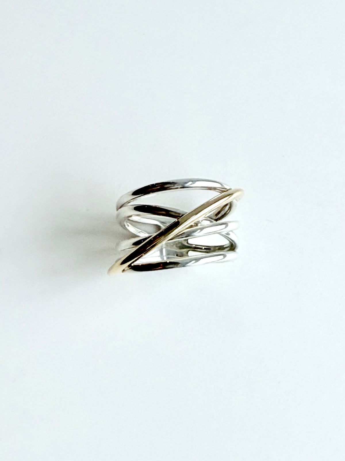 A minimalist two-tone ring with silver and gold bands, photographed on a clean white background.