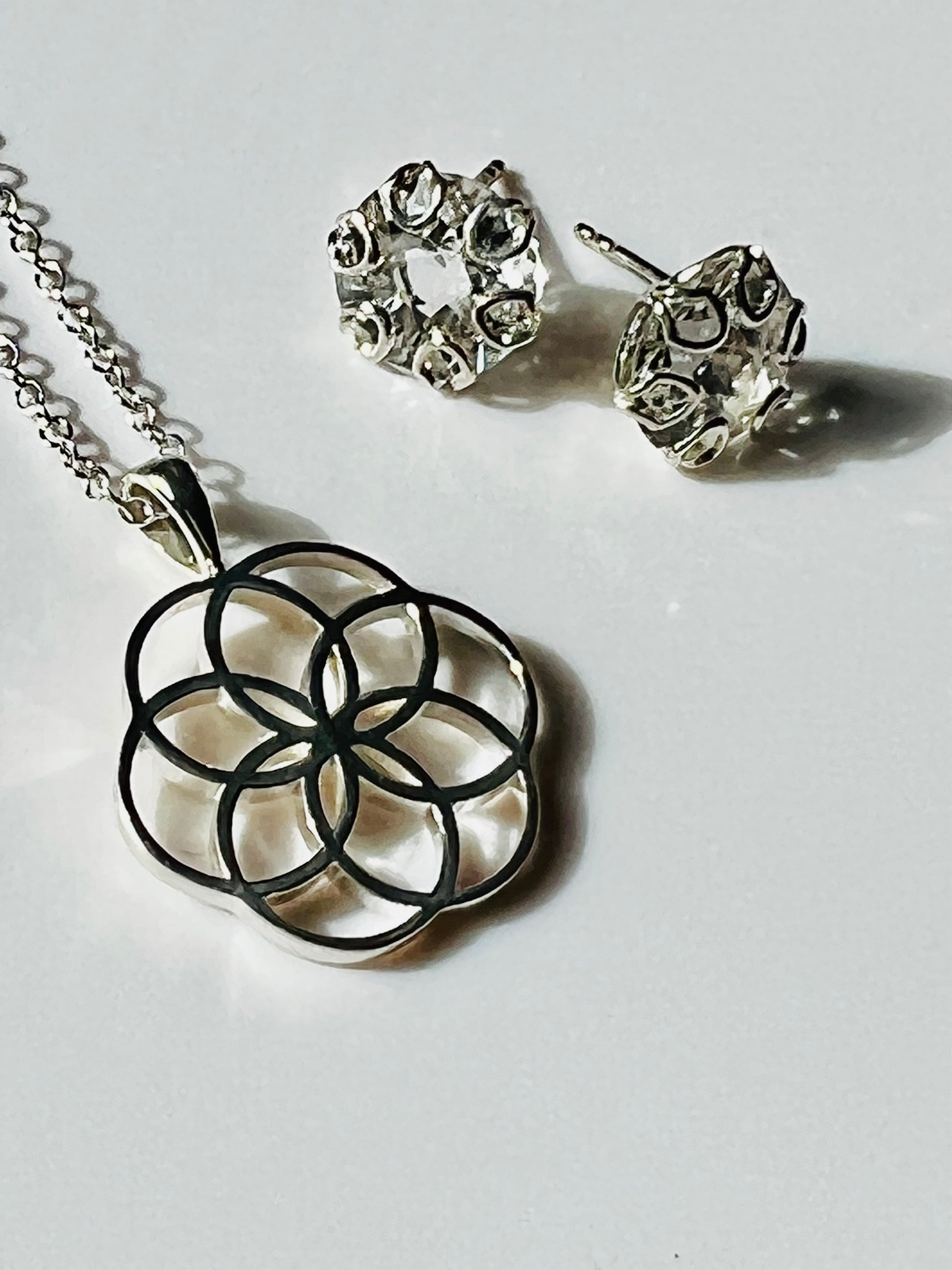 Rosette Fiore Open-work Pendant shown with Poppy Earring in White Topaz all by Hannah Daye & Co